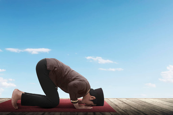 Side view of asian muslim man praying with blue sky background - Valokuva, kuva