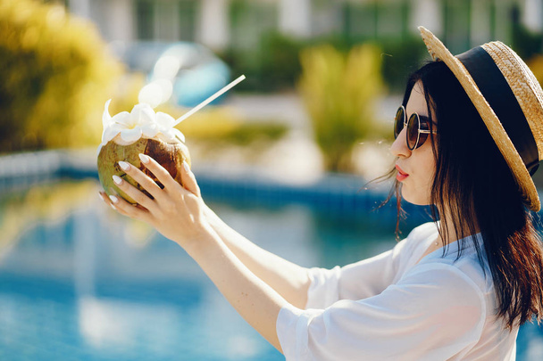 Mädchen trinkt frischen Saft aus einer Kokosnuss - Foto, Bild