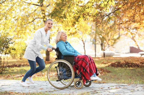 Disabled senior woman and young nurse in park - Fotoğraf, Görsel