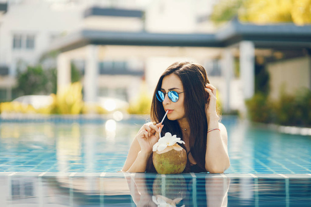 brunette girl eating fruit by the pool - Foto, Imagen
