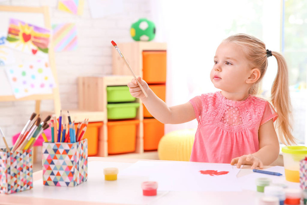 Little cute girl painting at table indoors - 写真・画像