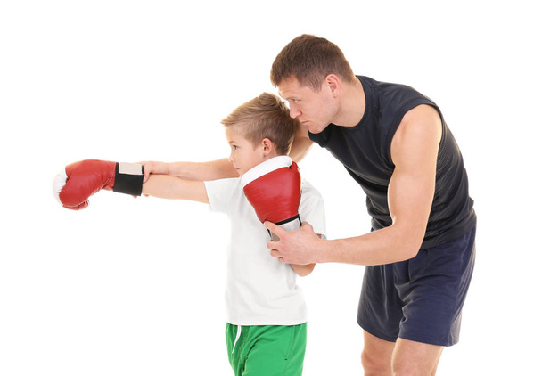 Cute little boy training with boxing coach on white background - Photo, image