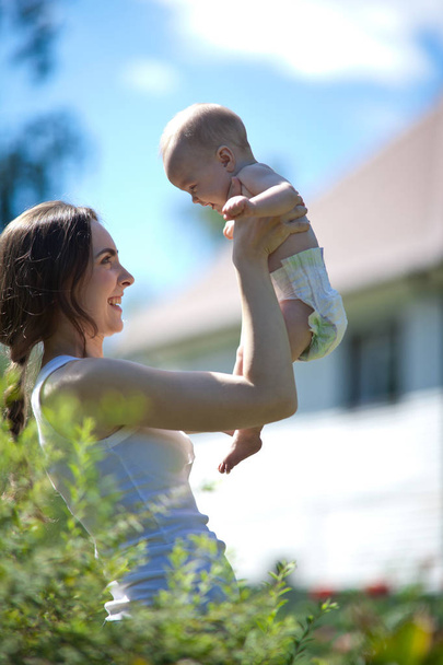 Happy woman holding in arm a baby outdoors - Photo, image