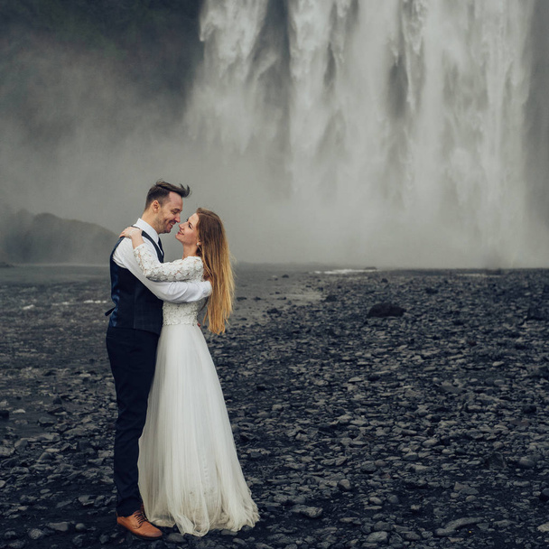 Married couple hugging waterfall at daytime - Foto, Bild
