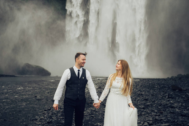 Married couple walking near waterfall at daytime - Fotó, kép