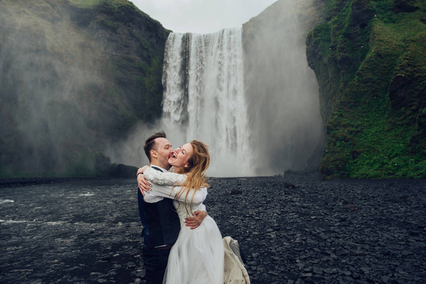 Married couple hugging waterfall at daytime - Foto, Imagen