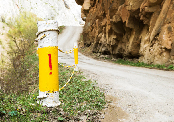 Postes de esgrima en una sección empinada de una carretera de montaña estrecha con una advertencia
 - Foto, Imagen