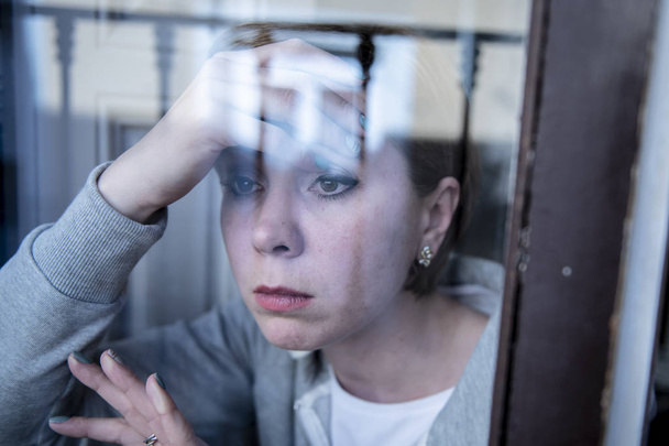 young beautiful depressed unhappy caucasian woman looking worried and sad through the window at home. feeling worthless and in pain. closeup. Depression and crisis concept - Foto, Bild