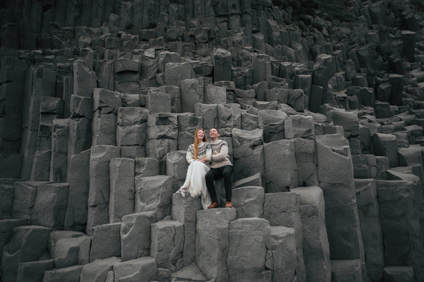 married couple in sweaters sitting on stones  - Photo, Image