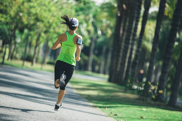 sporty young fitness woman running at tropical park - Valokuva, kuva