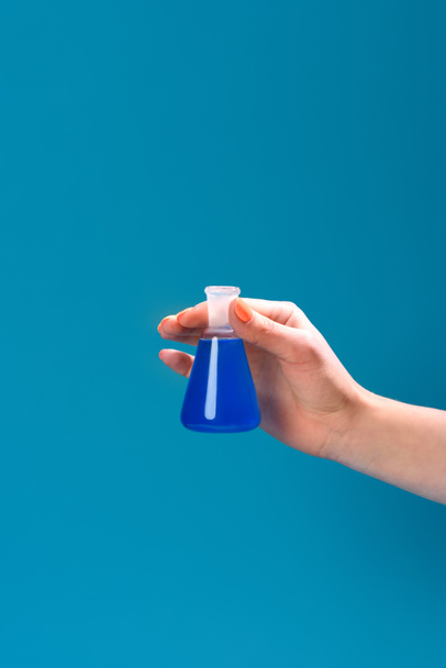 tiro recortado de mulher segurando frasco de líquido azul isolado em azul
 - Foto, Imagem