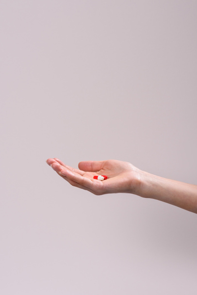 Oříznout záběr ženy držící haldy pilulek v ruce izolované na šedá - Fotografie, Obrázek
