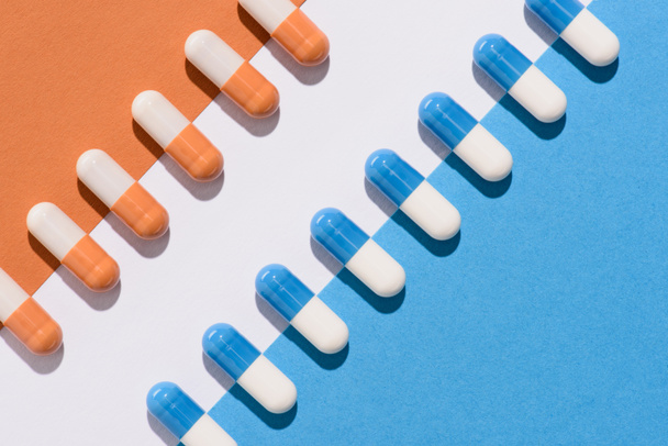 top view of blue and orange pills on colorful surface - Photo, Image