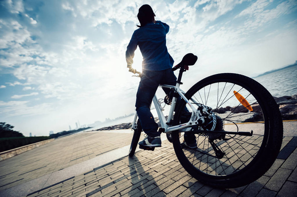 cyclist looking at the beautiful landscape while standing with bike at sunrise coast  - Foto, imagen
