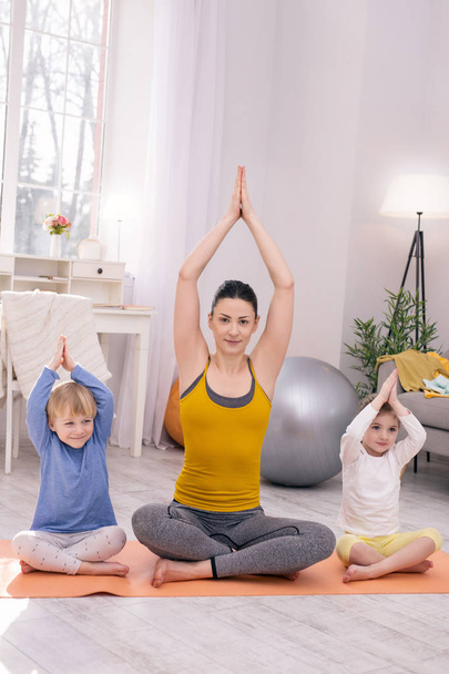 Happy mother and her children doing yoga - Foto, imagen