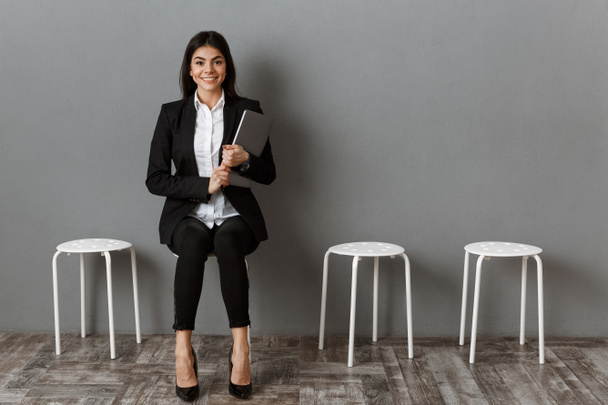 femme d'affaires souriante en costume avec ordinateur portable en attente d'un entretien d'embauche
 - Photo, image