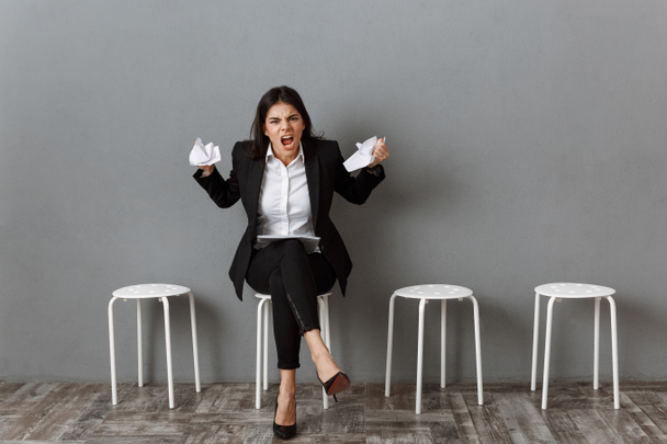 mulher de negócios irritada em terno com papéis embrulhados à espera de entrevista de emprego
 - Foto, Imagem