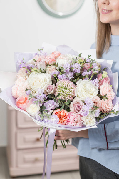 Sunny spring morning. Young happy woman holding a beautiful luxury bouquet of mixed flowers. the work of the florist at a flower shop - Foto, imagen