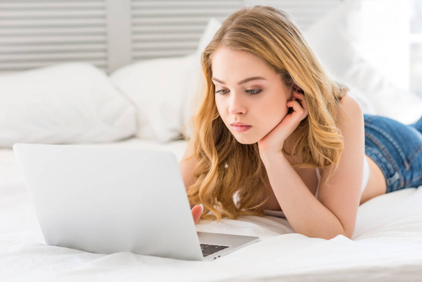 schöne junge Frau mit Laptop auf dem Bett - Foto, Bild