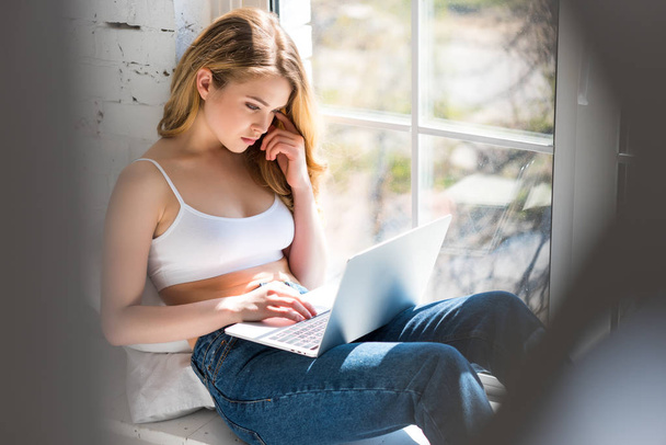 beautiful young woman using laptop on windowsill - Fotoğraf, Görsel
