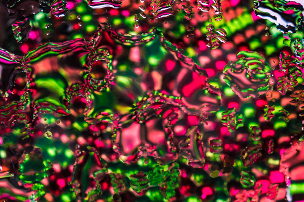 A horizontal bright colored blured texture of water drops and reflection of rainbow transparent water beads in green and red color - Photo, Image