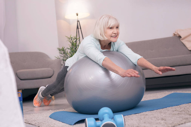 Pleasant elderly woman lying on exercise ball - Foto, Bild