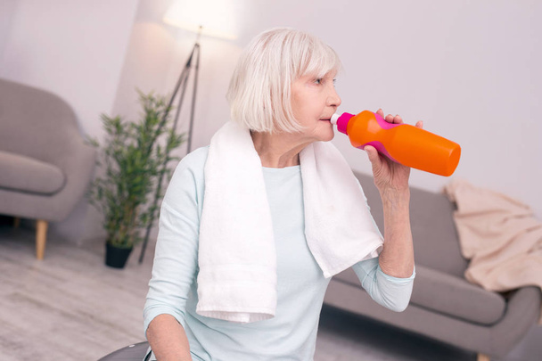 Pleasant senior woman drinking water after a workout - Фото, изображение