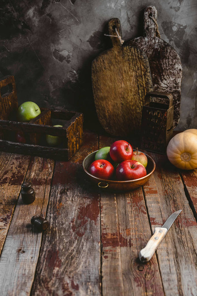 Schneidebretter, Reibe, Kürbis, Teller mit Äpfeln und Messer auf Holztisch  - Foto, Bild