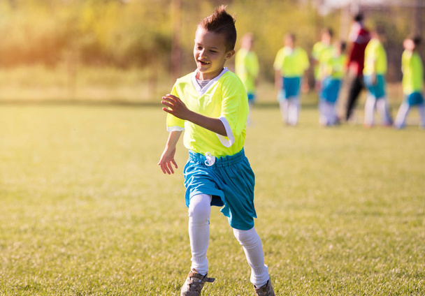 Chico pateando fútbol en el campo de deportes
 - Foto, imagen