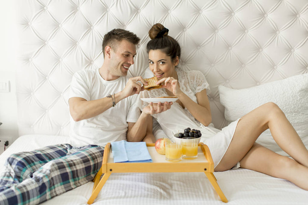 Jonge verliefde paar ontbijten in bed - Foto, afbeelding