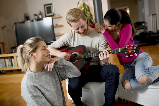 Młodzi ludzie o partii z gitara w pokoju - Zdjęcie, obraz