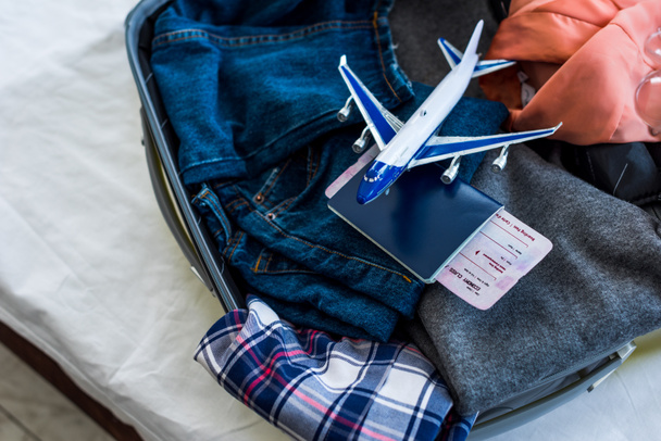 close up of suitcase with clothes, passport, air ticket and airplane model - Foto, immagini