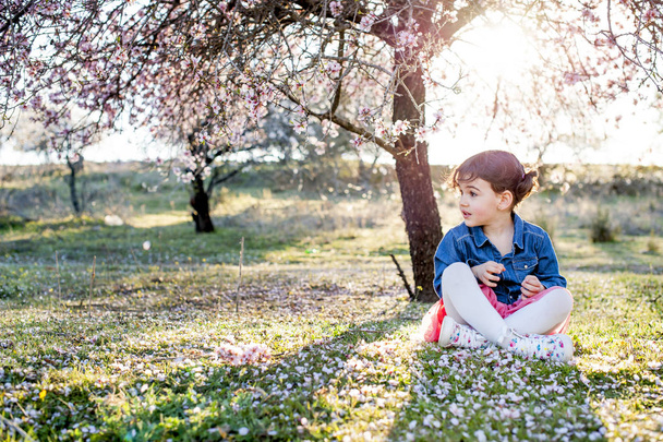 küçük kız bahar badem çiçeği içinde poz - Fotoğraf, Görsel