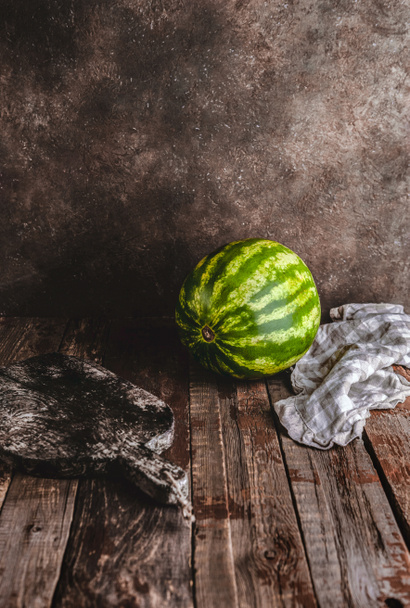 cutting board, watermelon and kitchen towel on rustic wooden table  - Fotografie, Obrázek