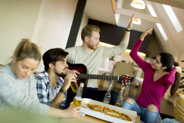 Ομάδα νέων ανθρώπων που έχοντας πίτσα κόμμα στο δωμάτιο - Φωτογραφία, εικόνα