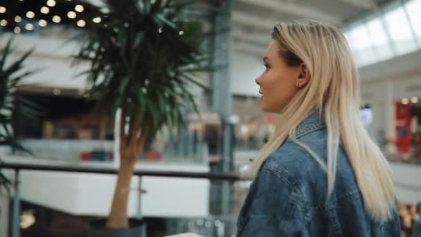 UKRAINE, LVIV - FEBRUARY 2, 2018: Charming blonde woman in jeans jacket walks around a shopping mall - Filmati, video