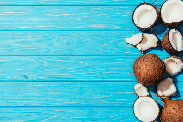 top view of whole coconuts and pieces on turquoise wooden surface  - Foto, Imagem