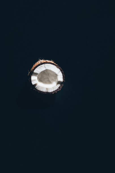 крупным планом вид половины вкусного здорового кокоса, выделенного на черном
 - Фото, изображение