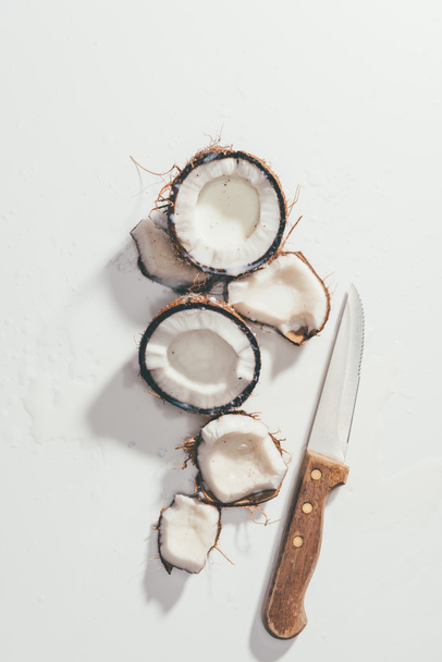 top view of pieces of natural healthy coconut and knife on white - Foto, Imagem