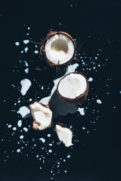 top view of coconut and fresh healthy coconut milk on black - Foto, immagini