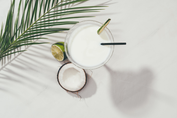 top view of coconut cocktail in glass with lime and drinking straw on white - Photo, Image