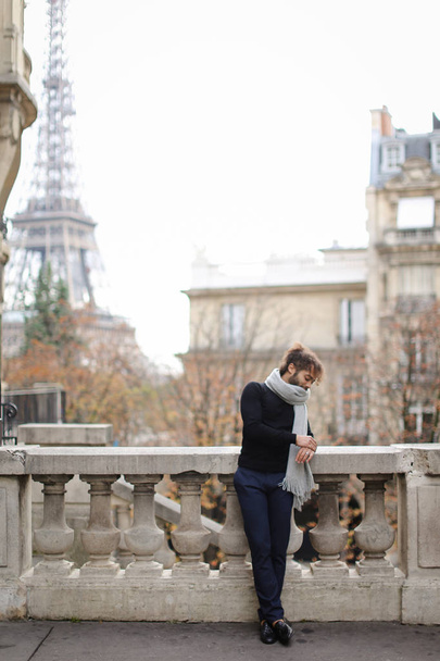 Afro-Américain debout près d'une rambarde en béton sur fond de Tour Eiffel à Paris
. - Photo, image