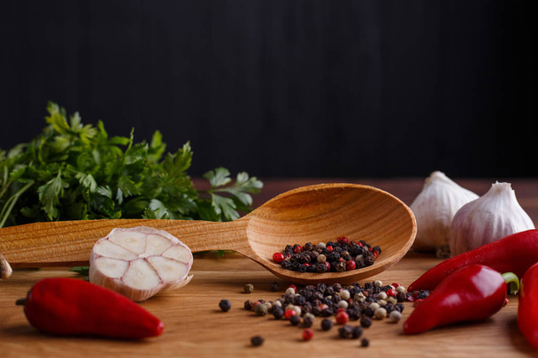Mixed peppers in a wooden spoon. Spices and herbs on kitchen tab - 写真・画像