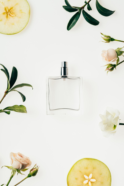 top view of glass bottle of perfume surrounded with flowers and apple slices isolated on white - 写真・画像
