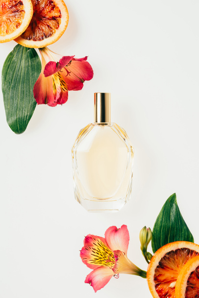 vista superior de la botella de perfume aromático con flores y rodajas de pomelo aisladas en blanco
 - Foto, Imagen