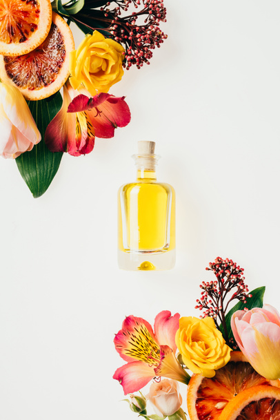top view of bottle of aromatic perfume with beautiful flowers and grapefruit slices isolated on white - Foto, Imagem