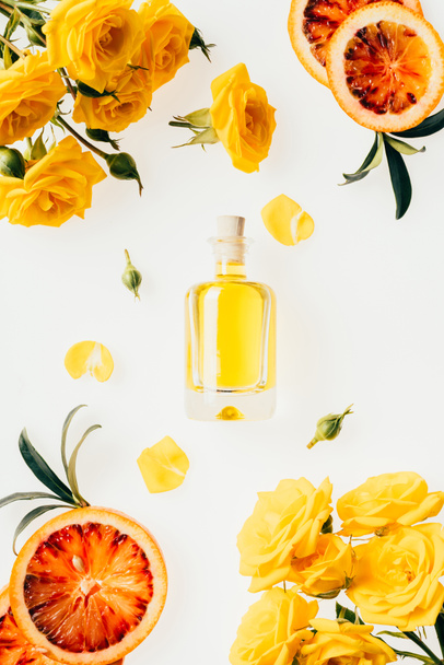 top view of bottle of perfume with beautiful flowers around on white - Foto, afbeelding