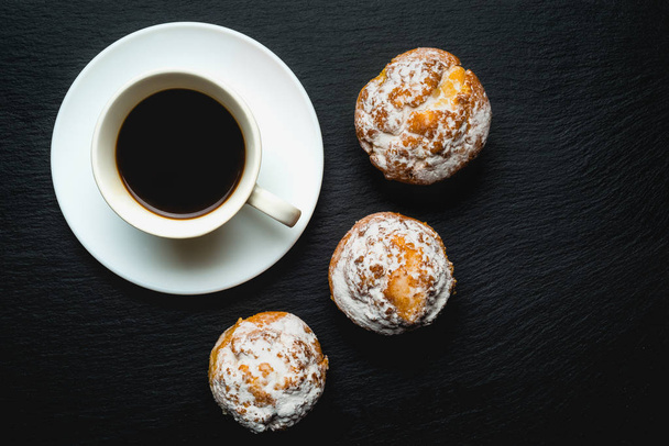 Draufsicht auf Kaffee mit Handwerkermuffins vor schwarzem Hintergrund - Foto, Bild