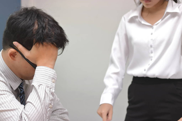 Mujer enojada jefe culpando a joven hombre asiático con las manos en la cara en la oficina
. - Foto, Imagen