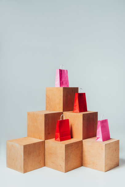 bolsas de compras rojas y rosadas en cubos de madera, concepto de venta de verano
 - Foto, Imagen